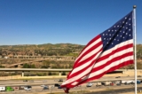 Xe hơi và xe tải chạy ngang qua một lá cờ Mỹ trên Xa lộ 91 ở Anaheim Hills, California, vào ngày 08/02/2023. (Ảnh: Patrick T. Fallon/AFP qua Getty Images)