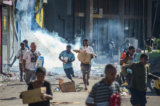 Mọi người mang theo hàng hóa bỏ chạy khi đám đông rời khỏi những cửa hàng với hàng hóa cướp được giữa tình trạng bất ổn ở Port Moresby hôm 10/01/2024. (Ảnh: Andrew Kutan/AFP qua Getty Images)