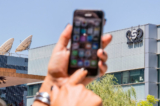 Một phụ nữ Israel sử dụng iPhone của mình trước tòa nhà nơi công ty NSO Group của Israel tọa lạc ở Herzliya, gần Tel Aviv, hôm 28/08/2016. (Ảnh: Jack Guez/AFP qua Getty Images)