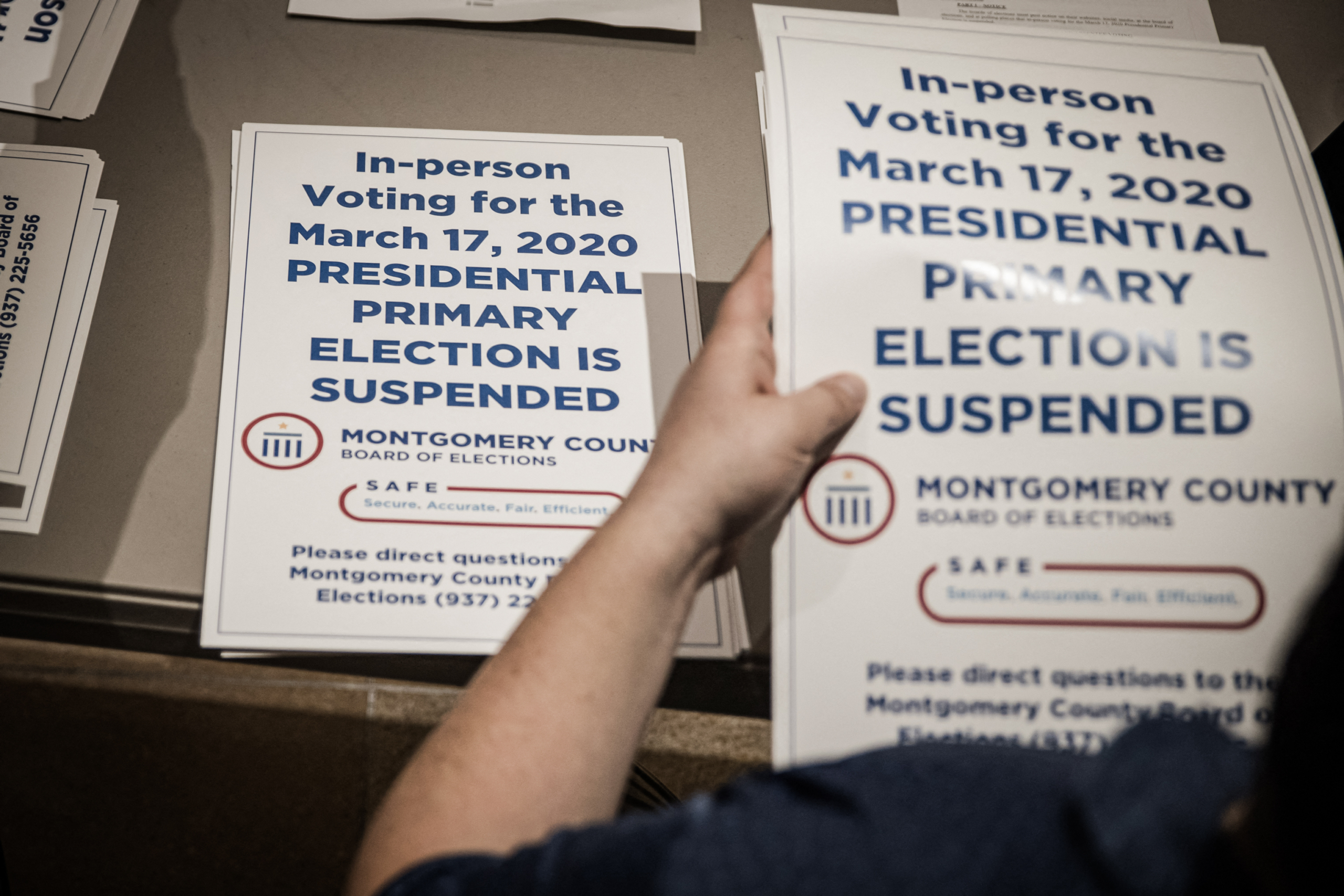 Các nhân viên bầu cử của quận phát các biển hiệu “tạm dừng bầu cử” để dán tại các điểm bỏ phiếu sau khi cuộc bầu cử sơ bộ bị hủy bỏ, ở Dayton, Ohio, vào ngày 17/03/2020. (Ảnh: Megan Jelinger/AFP qua Getty Images)