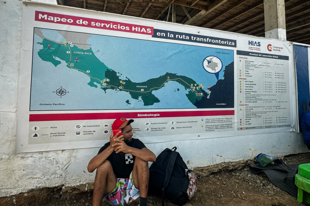 Một người di cư ngồi dưới một tấm bản đồ di cư chi tiết do một tổ chức phi chính phủ cung cấp tại trại di cư ở Darien Gap, Panama. (Ảnh: Darlene McCormick Sanchez/The Epoch Times.)