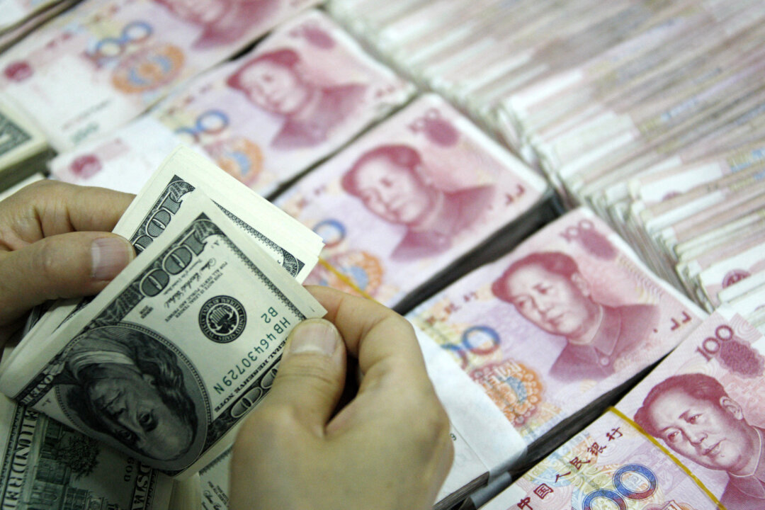 Bức ảnh chụp ngày 24/09/2013 này cho thấy những tờ tiền USD đang được đếm bên cạnh các xấp tiền 100 nhân dân tệ (RMB) tại một ngân hàng ở Hoài Bắc, tỉnh An Huy, miền đông Trung Quốc. Với các thỏa thuận từ London đến Singapore, Trung Quốc có tham vọng thiết lập một vai trò lớn hơn cho đồng nhân dân tệ trên thị trường toàn cầu nhằm thách thức vị thế thống trị của đồng USD. (Ảnh: STR/AFP qua Getty Images)