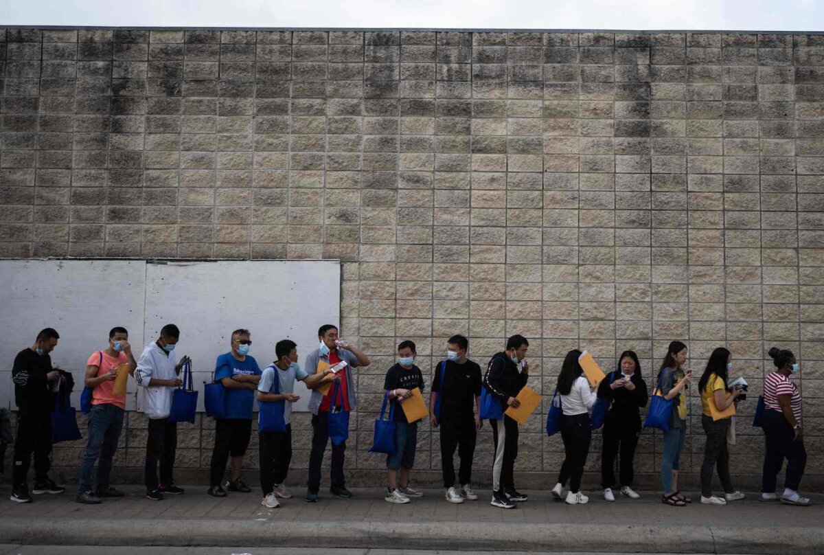 Những người nhập cư bất hợp pháp xếp hàng bên ngoài một trung tâm giải quyết thủ tục ở Brownsville, Texas, ngày 11/05/2023. (Ảnh: Andrew Caballero-Reynolds/AFP qua Getty Images)