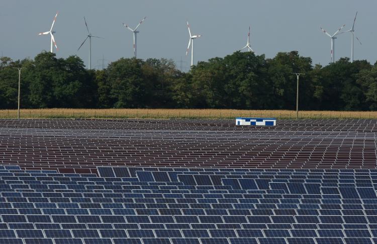 Năng lượng tái tạo: Tuabin gió quay phía sau một cánh đồng pin mặt trời. Năm 2010, đầu tư vào các nguồn năng lượng tái tạo, bao gồm phong năng, quang năng, và năng lượng đại dương, sẽ tăng vọt lên 5 tỷ USD. (Ảnh: Sean Gallup/Getty Images)