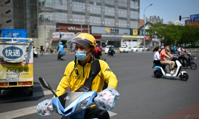 Một tài xế giao đồ ăn đeo khẩu trang đi xe đạp điện lái xe qua đường ở Bắc Kinh vào ngày 19/06/2020. (Ảnh: Wang Zhao/AFP qua Getty Images)