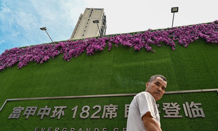 Một người đàn ông đi ngang qua một tòa nhà chung cư do Evergrande phát triển ở Thượng Hải hôm 24/09/2021. (Ảnh: Hector Retamal/AFP qua Getty Images)