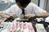 Một nhân viên đếm các tập tiền USD và nhân dân tệ tại một ngân hàng ở Thượng Hải, Trung Quốc, hôm 22/07/2005. (Ảnh: China Photos/Getty Images)