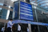 Người dân đi ngang qua màn hình hiển thị chỉ số chứng khoán Hang Seng tại khu Trung Hoàn, Hồng Kông, Trung Quốc, hôm 25/10/2022. (Ảnh: Lam Yik/Reuters)