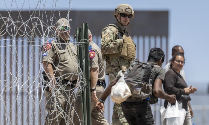 Một người lính Vệ binh Quốc gia Texas quan sát một người nhập cư bất hợp pháp bước vào một trại tạm ở El Paso, Texas, vào ngày 11/05/2023. (Ảnh: John Moore/Getty Images)