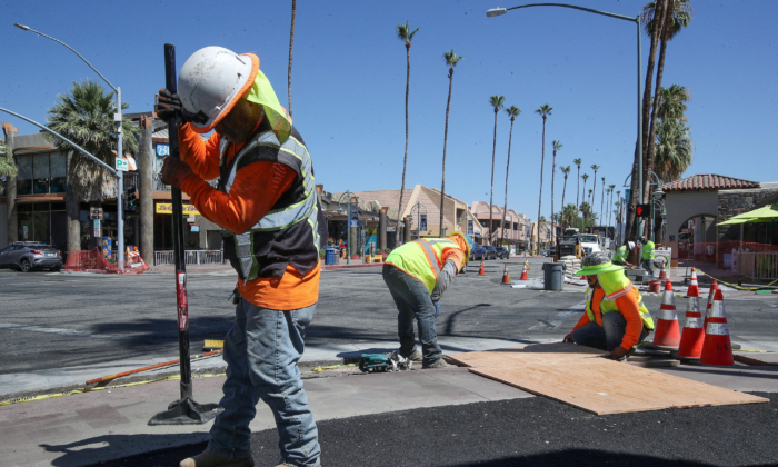 Các công nhân xây dựng đang lát vỉa hè mới ở trung tâm thành phố Palm Springs, California, vào tháng 07/2023, một trong khoảng 35,000 dự án cơ sở hạ tầng đang được tiến hành hoặc sắp bắt đầu khi 700 tỷ USD tiền liên bang bắt đầu được phân bổ đến các tiểu bang, quận, và thành phố trên khắp đất nước. (Ảnh: Jay Calderon/USA Today Network qua Reuters)