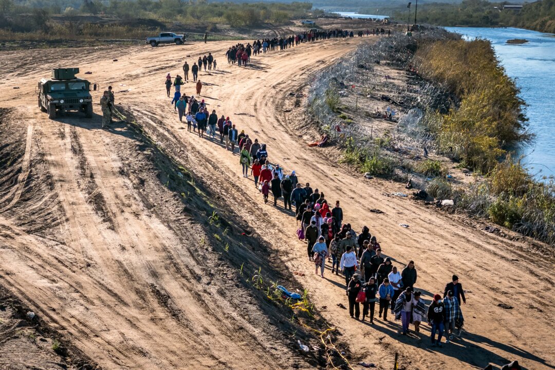 Bức ảnh chụp từ trên không này cho thấy một nhóm gồm hơn 1,000 người nhập cư đi tới một trung tâm giải quyết thủ tục tại hiện trường của lực lượng Tuần tra Biên giới Hoa Kỳ sau khi họ vượt sông Rio Grande từ Mexico ở Eagle Pass, Texas, vào ngày 18/12/2023. (Ảnh: John Moore/Getty Images)