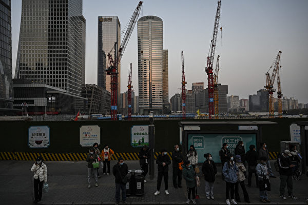 Người dân chờ xe buýt tại một trạm xe buýt gần một công trường xây dựng ở khu thương mại trung tâm ở Bắc Kinh vào ngày 26/03/2023. (Ảnh: Jade Gao/AFP/Getty Images)