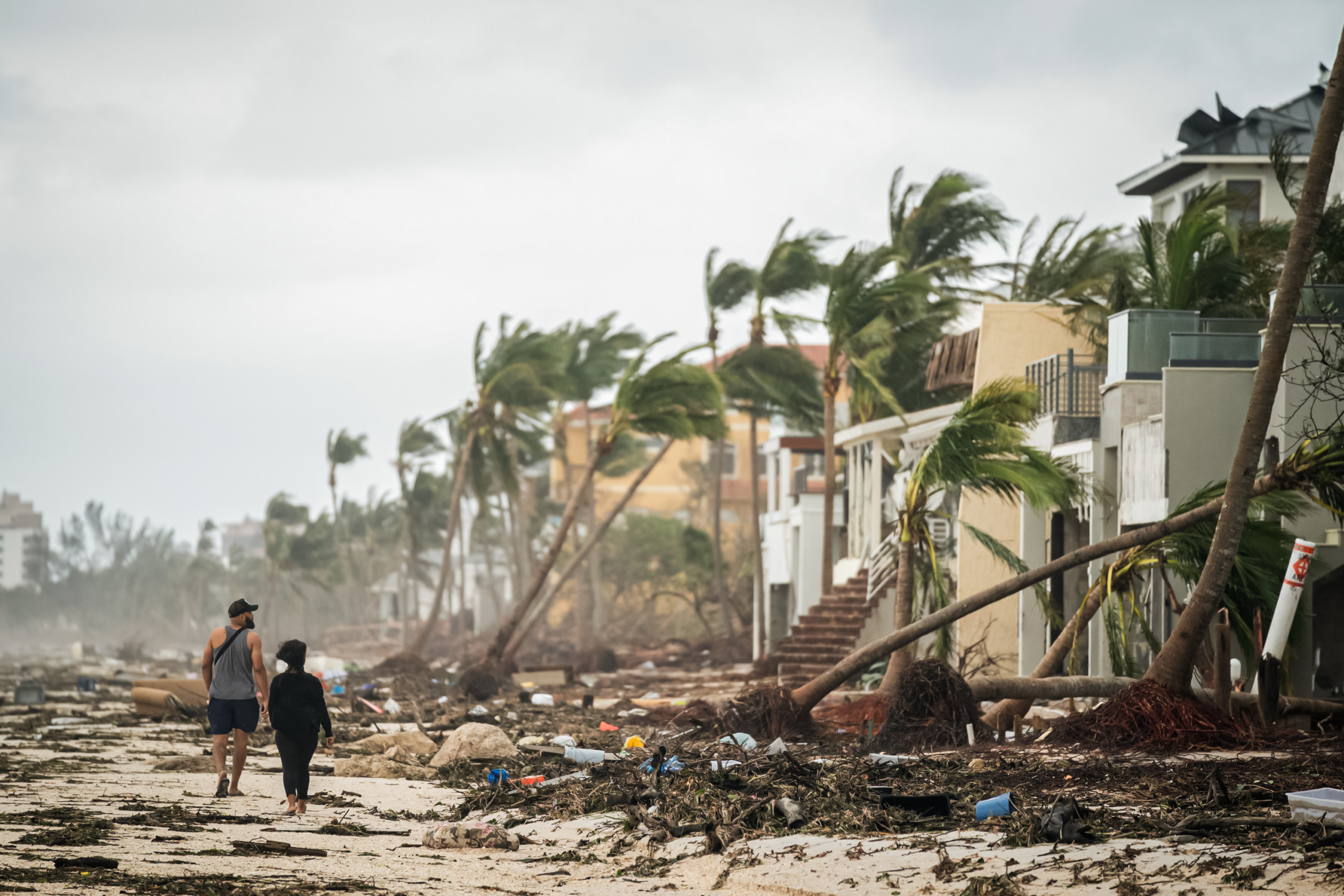 Người dân đi bộ dọc bãi biển, nhìn nhà cửa bị hư hại do Bão Ian ở Bonita Springs, Florida vào ngày 29 /09/2022. (Ảnh: Sean Rayford/Getty Images)