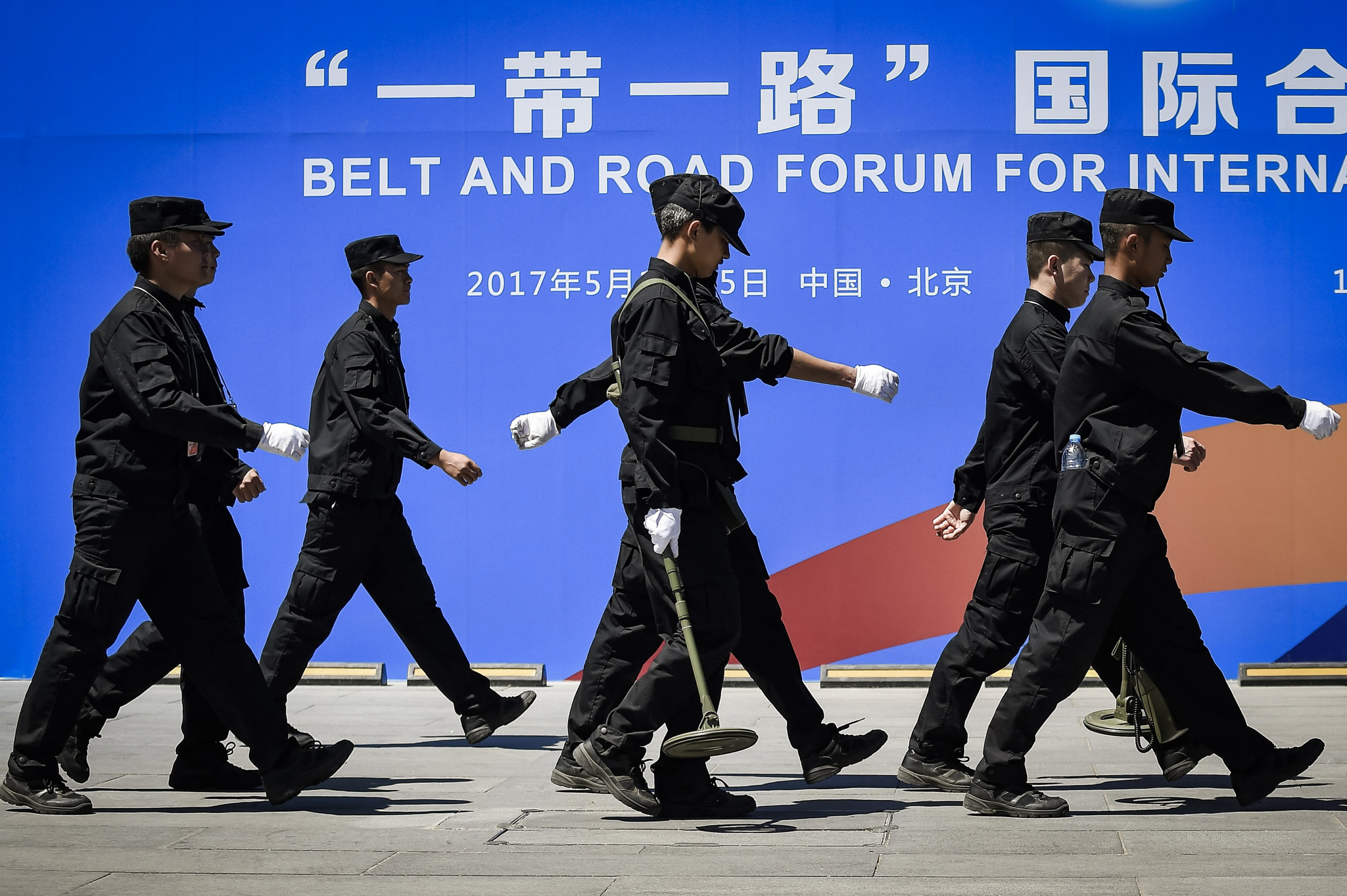 Các nhân viên bảo vệ đi ngang qua một tấm bảng quảng cáo cho Diễn đàn Hợp tác Quốc tế Vành đai và Con đường tại địa điểm tổ chức diễn đàn ở Bắc Kinh vào ngày 13/05/2017. (Ảnh: Wang Zhao/AFP qua Getty Images)