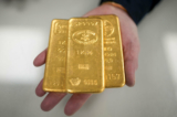 Một người buôn vàng với ba thỏi vàng nặng 1 kg ở Birmingham, Anh, vào ngày 13/12/2023. (Ảnh: Christopher Furlong/Getty Images)