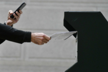 Một người đàn ông tự chụp ảnh mình đang bỏ phiếu vào một thùng phiếu chính thức trong khi một hàng dài cử tri xếp hàng bên ngoài Tòa Thị chính Philadelphia tại trạm bỏ phiếu vệ tinh ở Philadelphia, Pennsylvania, vào ngày 27/10/2020. (Ảnh: Mark Makela/Getty Images)