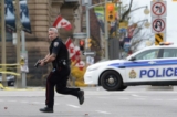 Một viên cảnh sát đang chạy cùng với khẩu súng trên tay ở Ottawa vào ngày 22/10/2014, trong một vụ tấn công của ông Michael Zehaf Bibeau vào Parliament Hill. Ông Bibeau đã bắn Hạ sĩ Nathan Cirillo và làm bị thương một nhân viên bảo an trước khi bị trung sĩ của Nghị viện bắn hạ. (Ảnh: The Canadian Press/Sean Kilpatrick)