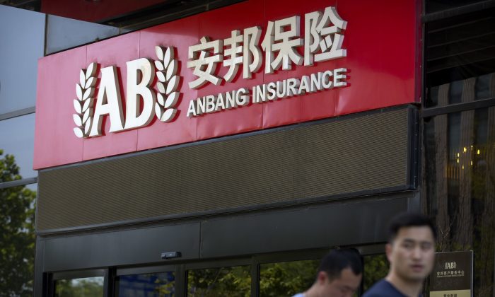 Khách bộ hành đi ngang qua lối vào một văn phòng của Tập đoàn Bảo hiểm An Bang (Anbang Insurance Group) ở Bắc Kinh, hôm 14/06. (Ảnh: Mark Schiefelbein/AP Photo)