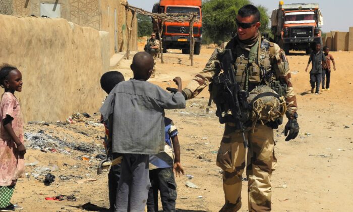 Một người lính thuộc phái bộ Barkhane của Pháp đứng cạnh trẻ em khi anh đang tuần tra ở I-n-Tillit ở Mali, vào ngày 01/11/2017. (Ảnh: Daphne Benoit/AFP qua Getty Images)