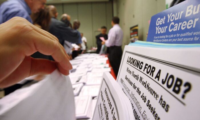 Người tìm việc xem các tờ rơi tuyển dụng tại triển lãm WorkSource. (Ảnh: David McNew/Getty Images)