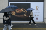 Một khách bộ hành đi ngang qua tấm biển quảng cáo vàng ở Bắc Kinh, hôm 10/04/2024. (Ảnh: Wang Zhao/AFP)
