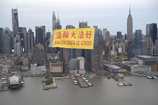 Một biểu ngữ lớn ghi dòng chữ “Pháp Luân Đại Pháp hảo” bằng Hoa ngữ và Anh ngữ đang bay trên bầu trời dọc theo sông Hudson ở New York, với khung cảnh tráng lệ của Manhattan ở phía sau, hôm 21/04/2024. (Ảnh: Do các học viên Pháp Luân Công cung cấp)