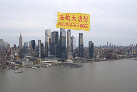 Một biểu ngữ lớn ghi dòng chữ “Pháp Luân Đại Pháp hảo” bằng Hoa ngữ và Anh ngữ đang bay trên bầu trời dọc theo sông Hudson ở New York, với khung cảnh tráng lệ của Manhattan ở phía sau, hôm 21/04/2024. (Ảnh: Do các học viên Pháp Luân Công cung cấp)