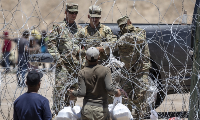 Các binh sĩ Vệ binh Quốc gia Texas phong tỏa một đoạn dây thép gai bao quanh trại di cư tạm thời khi một người nhập cư cố gắng trở về mang theo thức ăn cho gia đình ở El Paso, Texas, vào ngày 11/05/2023. (Ảnh: John Moore/Getty Images)