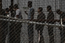 Những người nhập cư bất hợp pháp chờ dọc bức tường biên giới để lên xe buýt sau khi tự ra trình diện trước các nhân viên Tuần tra Biên giới và Cục Quan thuế và Bảo vệ Biên giới Hoa Kỳ (CBP) ở biên giới Hoa Kỳ-Mexico ở El Paso, Texas, vào ngày 12/05/2023. (Ảnh: Patrick T. Fallon/ AFP qua Getty Images)