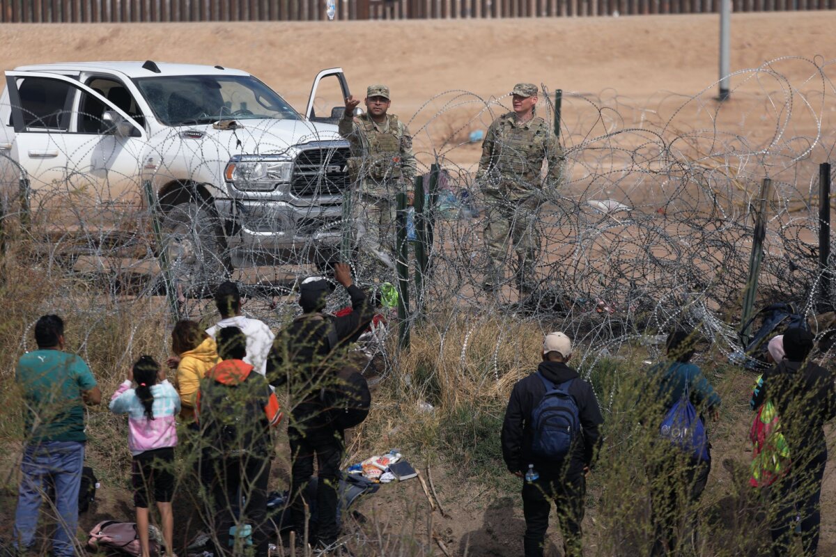 Nhân viên của Lực lượng Vệ binh Quốc gia Texas ngăn cản những người di cư từ Venezuela vượt qua hàng rào thép gai để đến Biên giới Khu vực El Paso sau khi băng qua sông Rio Grande từ Ciudad Juarez, Tiểu bang Chihuahua, Mexico, hôm 29/02/2024. (Ảnh: Herika Martinez/AFP qua Getty Images) )