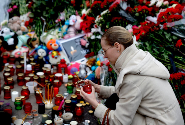 Một phụ nữ thắp nến tại đài tưởng niệm các nạn nhân của vụ xả súng hôm 22/03/2024 tại địa điểm hòa nhạc Crocus City Hall ở Moscow, hôm 24/03/2024. (Ảnh: Maxim Shemetov/Reuters)