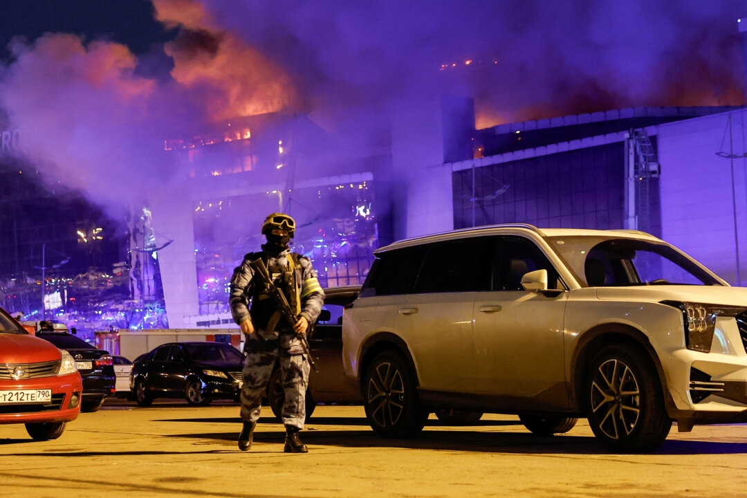 Một nhân viên chấp pháp Nga đi bộ tại khu vực đậu xe gần địa điểm tổ chức buổi hòa nhạc Crocus City Hall đang bốc cháy sau vụ xả súng, bên ngoài Moscow hôm 22/03/2024. (Ảnh: Maxim Shemetov/Reuters)