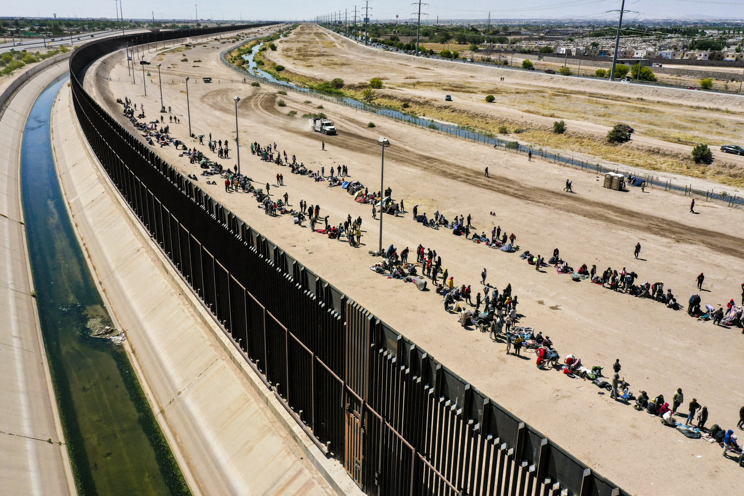 (Ảnh phía trên) Những người di cư ngồi trên một chuyến tàu chở hàng đang trên đường đến biên giới Hoa Kỳ-Mexico gần Ciudad Juarez, Mexico, vào ngày 10/05/2023. (Ảnh bên dưới) Những người nhập cư bất hợp pháp chờ các nhân viên Tuần tra Biên giới dọc theo bức tường biên giới ở El Paso, Texas, vào ngày 11/05/2023. (Ảnh: John Moore/Getty Images, Patrick T. Fallon/AFP qua Getty Images)