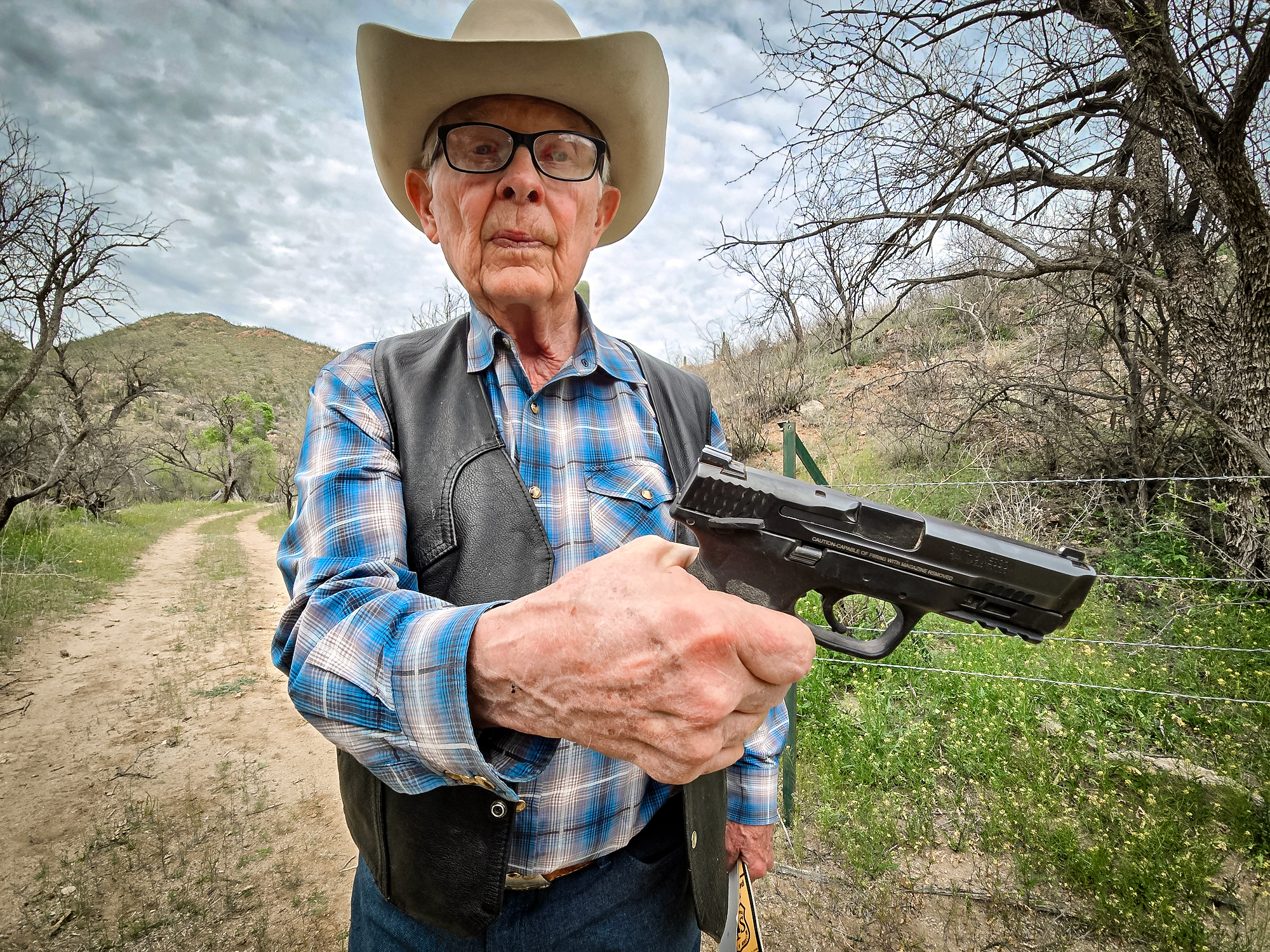 Chủ trang trại chăn nuôi gia súc Jim Chilton cho xem khẩu súng lục cỡ nòng 40 mà ông mang theo khi ra ngoài tại trang trại rộng 50,000 mẫu Anh của mình ở Arivaca, Arizona, hôm 22/03/2024. (Ảnh: Allan Stein/The Epoch Times)