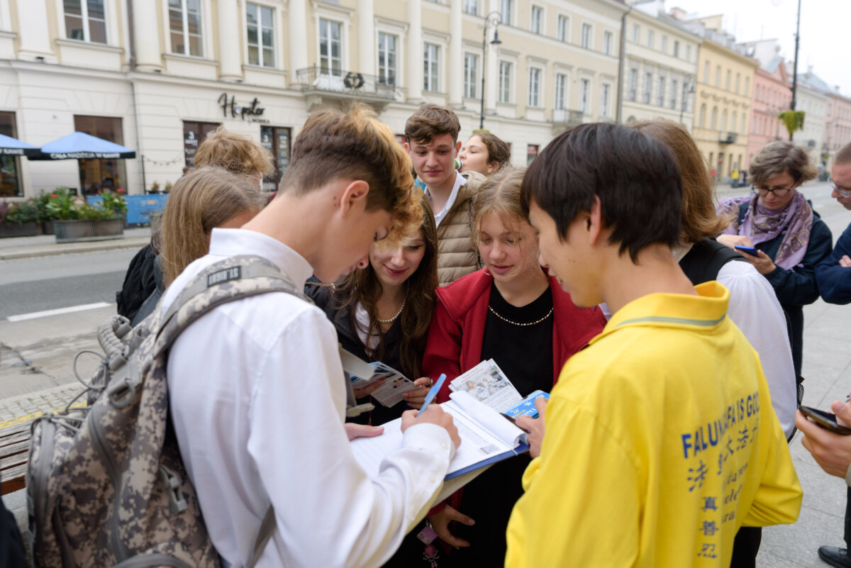 Khách bộ hành ký tên cho một cuộc thỉnh nguyện do một học viên Pháp Luân Đại Pháp tổ chức trong cuộc tuần hành qua trung tâm Warsaw, Ba Lan, vào ngày 09/09/2022. (Ảnh: Mihut Savu/The Epoch Times)
