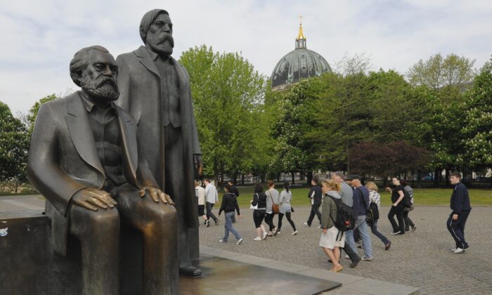 Du khách đi ngang qua bức tượng của Karl Marx (1818–1883) và Friedrich Engels (1820–1895) ở trung tâm thủ đô Berlin ngày 28/04/2009. (Ảnh: Theo Heimann /DDP/AFP via Getty Images)
