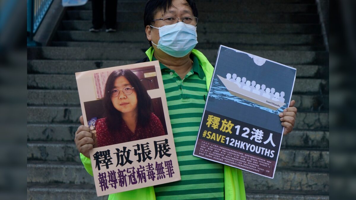 Một nhà hoạt động ủng hộ dân chủ giương cao tấm biển kêu gọi chính quyền Trung Quốc thả ký giả công dân Trương Triển cùng 12 người Hồng Kông bị giam giữ bên ngoài văn phòng liên lạc của chính quyền trung ương Trung Quốc, tại Hồng Kông, ngày 28/12/2020. (Ảnh: Kin Cheung/AP Photo)