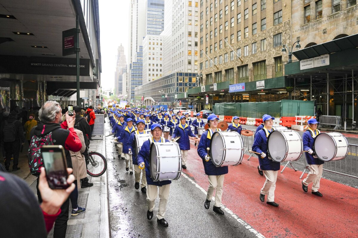 Khách bộ hành đang theo dõi ban nhạc Thiên quốc Nhạc đoàn biểu diễn trong cuộc diễn hành kỷ niệm Ngày Pháp Luân Đại Pháp Thế giới, tại thành phố New York, hôm 10/05/2024. (Ảnh: Samira Bouaou/The Epoch Times)