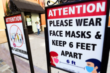 Các biển báo nhắc nhở người dân thực hiện giãn cách xã hội và đeo khẩu trang vẫn được dán tại một trung tâm mua sắm ở California vào ngày 14/06/2021. (Ảnh: Frederic J. Brown/AFP qua Getty Images)
