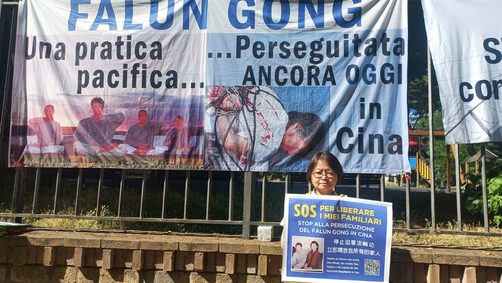 Học viên Pháp Luân Công Triệu Lý Lực cầm tấm biển ghi “Cứu giúp người thân” trong cuộc biểu tình. (Ảnh: The Epoch Times)