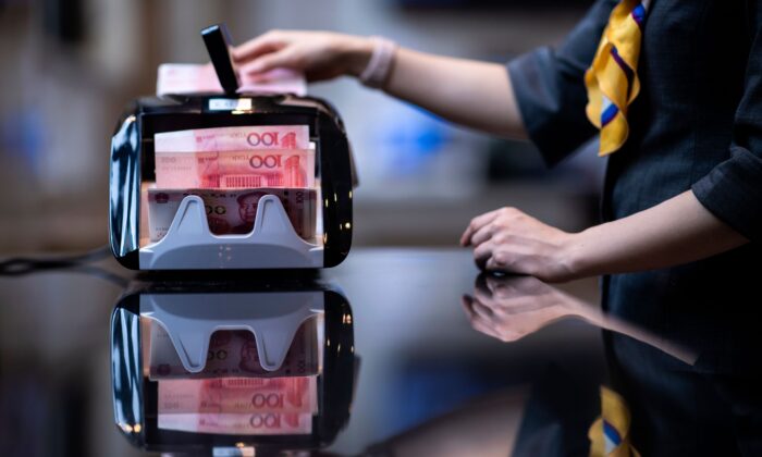 Một nhân viên ngân hàng sử dụng máy đếm tiền để đếm những tờ 100 nhân dân tệ tại một ngân hàng ở Thượng Hải, Trung Quốc, trong một bức ảnh tư liệu. (Ảnh: Johannes Eisele/AFP qua Getty Images)