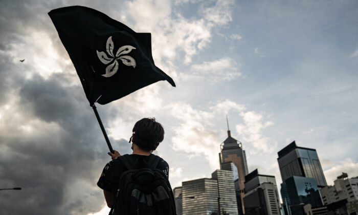 Một người đàn ông vẫy cờ Hồng Kông màu đen trên một con đường bên ngoài Khu liên hợp Hội đồng Lập pháp ở Hồng Kông vào ngày 01/07/2019. (Ảnh: Anthony Kwan/Getty Images)