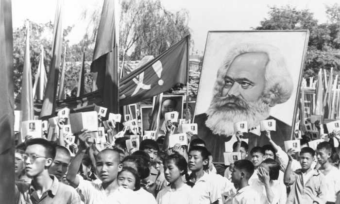 Trong một bức ảnh tư liệu, những thanh niên có mặt tại một cuộc tập hợp trong thời kỳ cao điểm của cuộc biến động Hồng Vệ Binh giơ cao bản sao các bài viết được sưu tầm của Chủ tịch Đảng Cộng sản Mao Trạch Đông, thường được gọi là Tiểu Hồng Thư của Mao, và mang theo một tấm bích chương hình Karl Marx. (Ảnh: AP Photo, Tư liệu)
