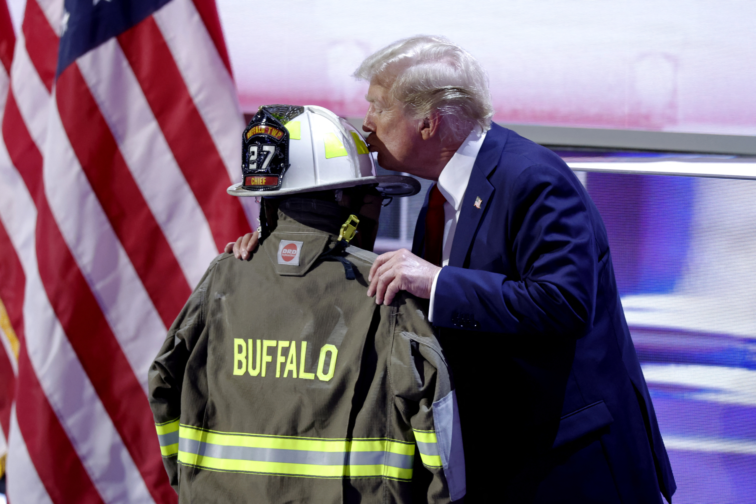 Cựu tổng thống và là ứng cử viên tổng thống năm 2024 của Đảng Cộng Hòa Donald Trump hôn chiếc mũ bảo hiểm và áo khoác nhân viên cứu hỏa của ông Corey Comperatore, người đã thiệt mạng tại một cuộc vận động tranh cử nơi ông Trump sống sót sau một nỗ lực ám sát, khi ông chấp nhận đề cử của đảng vào ngày cuối cùng của Hội nghị Quốc gia Đảng Cộng Hòa năm 2024 tại Diễn đàn Fiserv ở Milwaukee, Wisconsin, hôm 18/07/2024. (Ảnh: Kamil Krzaczynski/AFP qua Getty Images)